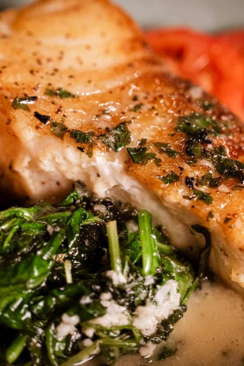 Pan-seared fish with sautéed spinach and butter sauce
