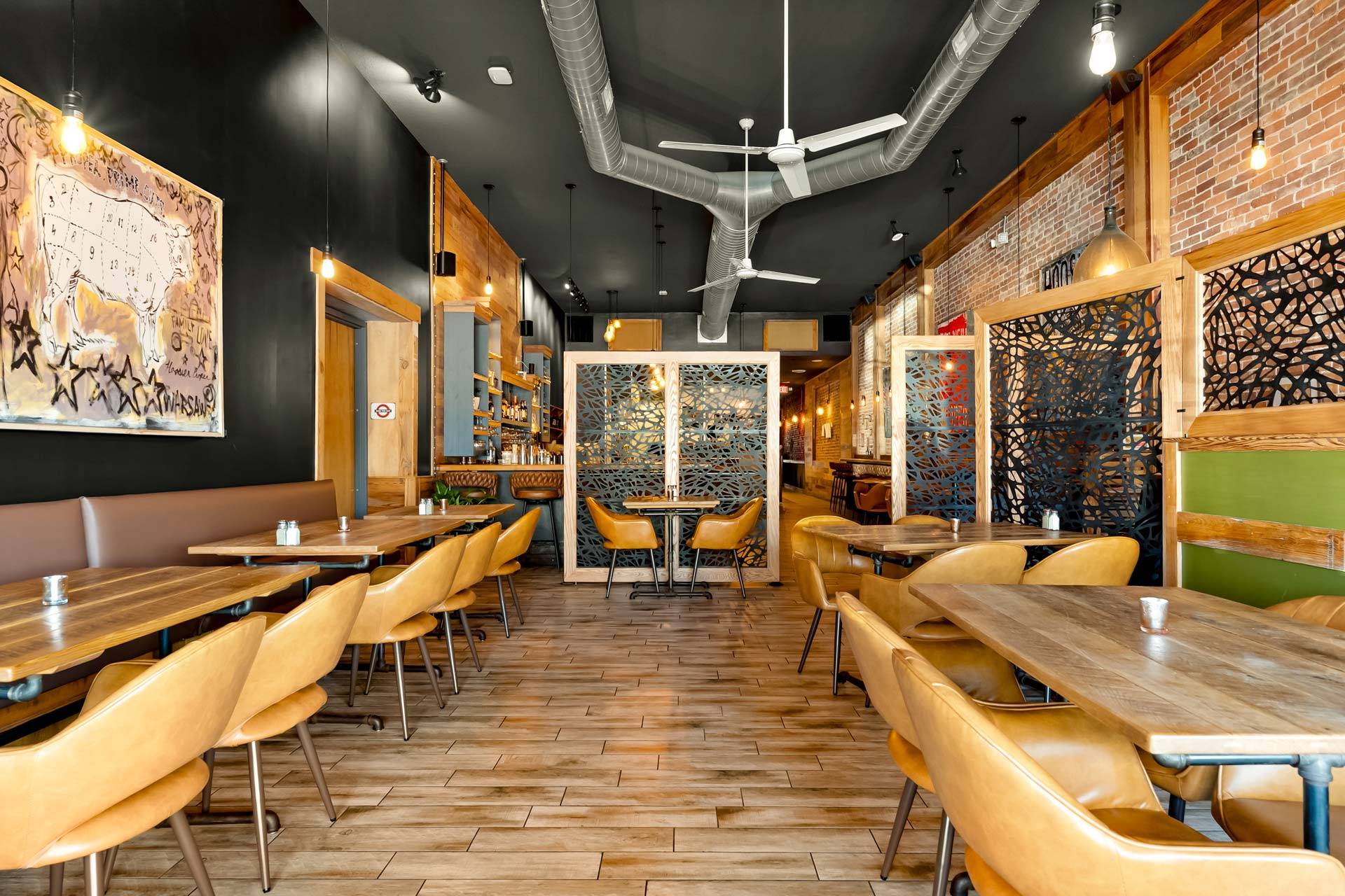 Main dining room with tan leather chairs, brick, and custom artwork