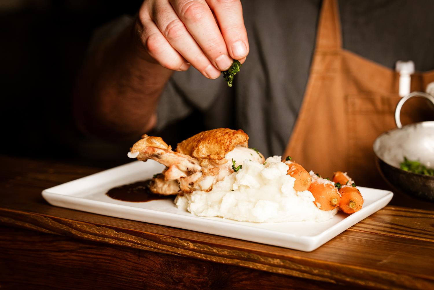 Plating roasted chicken with mashed potatoes and carrots