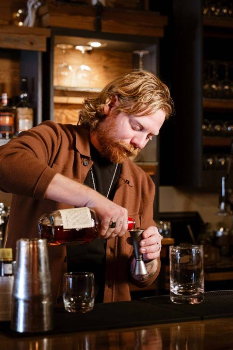 Bartender pouring a whiskey pour into a jigger
