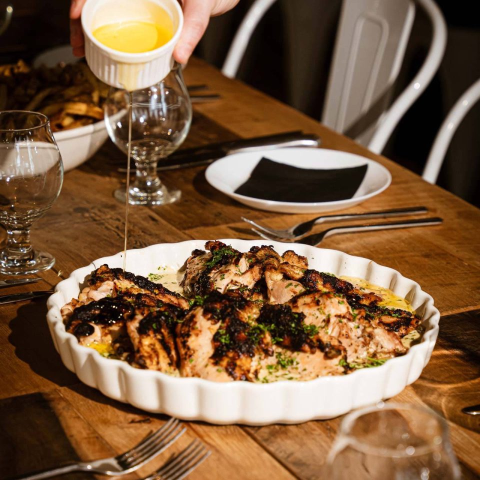 Butter poured over family-style roasted chicken platter