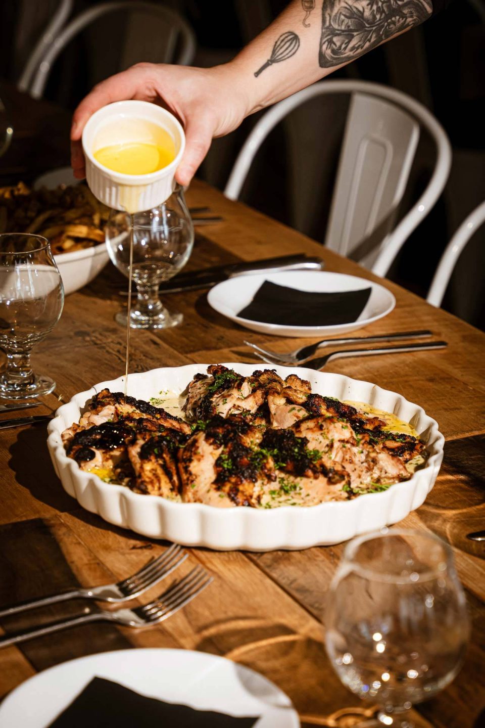Butter poured over a family-style roasted chicken platter