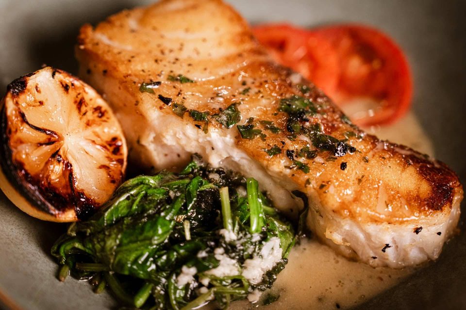 Pan-seared fish with charred lemon and sautéed spinach